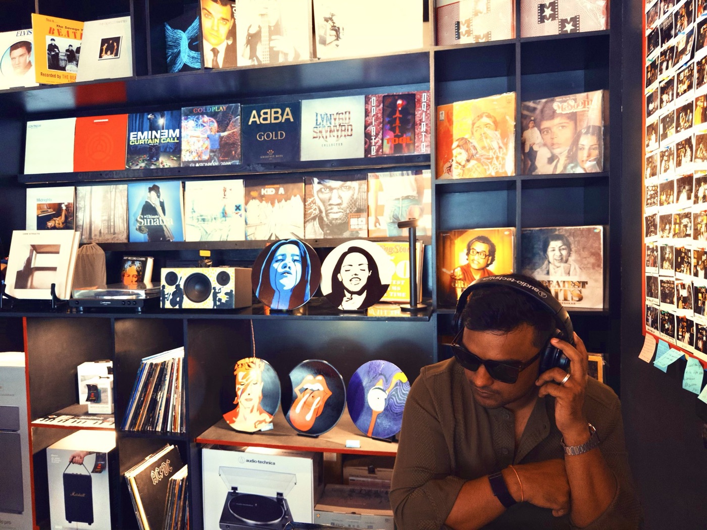 Rahul in a record store, headphones on, surrounded by vinyl